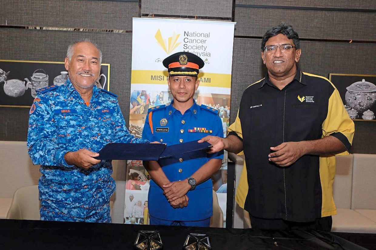 Thein (left) exchanging documents with Dr Murallitharan after the MoU signing witnessed by Lt Kol (PA) Kamarulsyah.